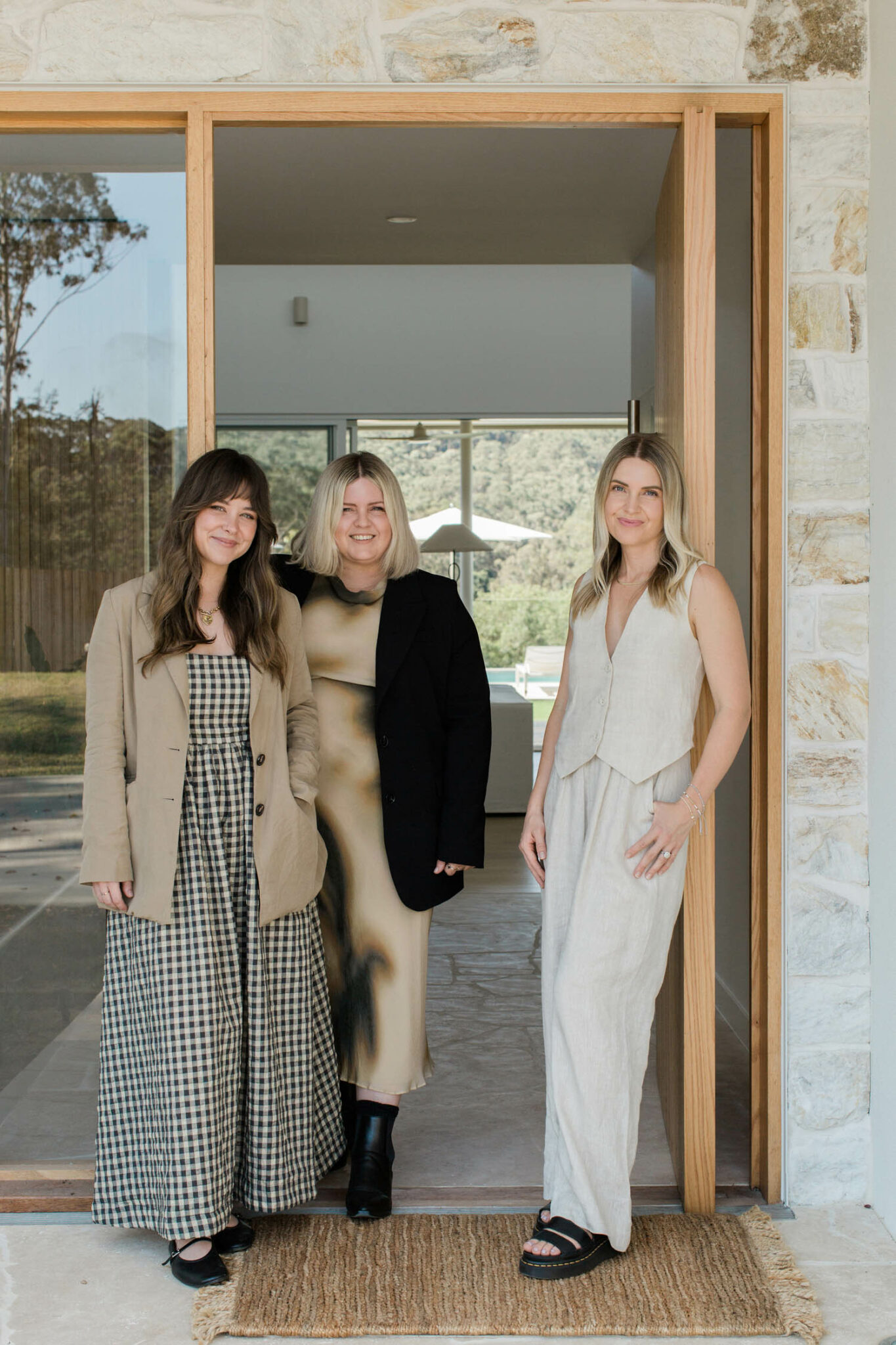 Three women standing in a doorway with a stone detailed entrance.