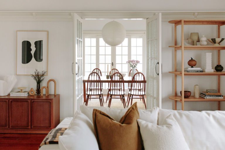 A shot of a dining room from a lounge room with vintage styling and a white lounge.