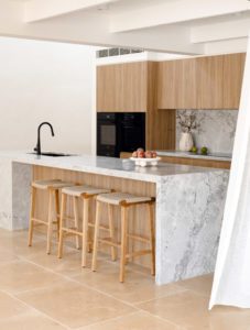 A modern kitchen with stone bench tops and wooden cabinetry.