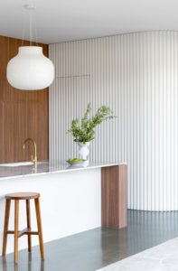 A modern, architect designed kitchen, complete with walnut cabinetry, stone bench top and walnut and rattan kitchen stools.