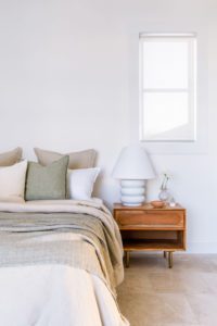 A serene bedroom with beige and sage green bedlinen.