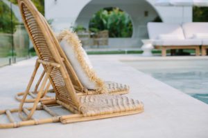 Cane sun loungers beside a pool area.