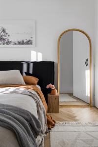 An arched cane mirror leans up against the wall of a linen bedhead bedroom.