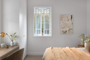 A modern bedroom styled with terracotta toned linen and fresh white flowers.