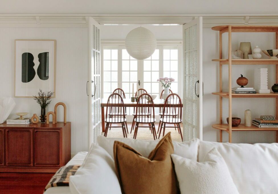 A shot of a dining room from a lounge room with vintage styling and a white lounge.